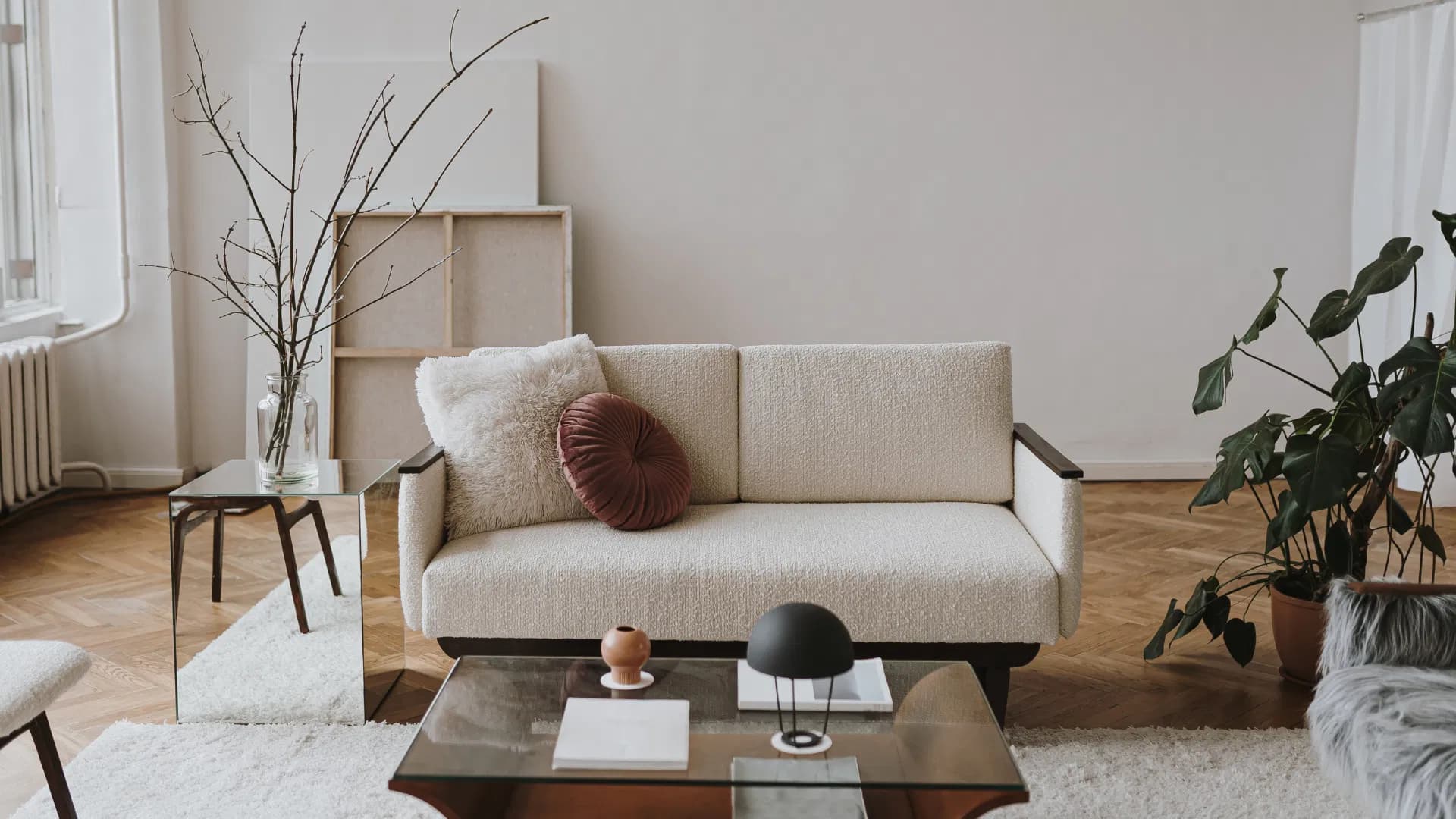 Bright modern living room with a cream boucle sofa, glass coffee table and houseplants